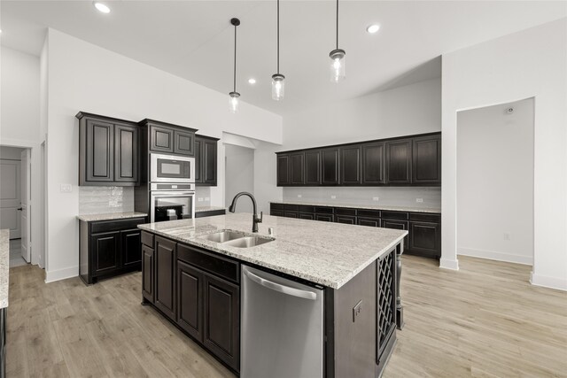 kitchen with tasteful backsplash, a kitchen island with sink, sink, and appliances with stainless steel finishes