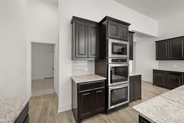 kitchen featuring tasteful backsplash, built in microwave, light hardwood / wood-style flooring, and light stone countertops