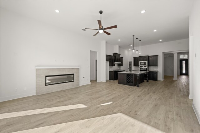 kitchen with ceiling fan, light wood-type flooring, an island with sink, a breakfast bar area, and stainless steel appliances