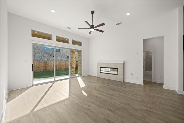 unfurnished living room with ceiling fan, wood-type flooring, and a fireplace