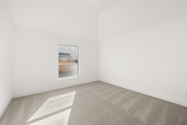 carpeted spare room with high vaulted ceiling