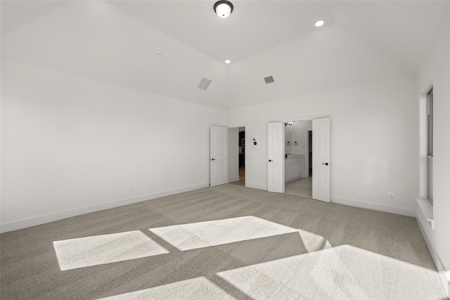 unfurnished bedroom featuring light carpet and high vaulted ceiling