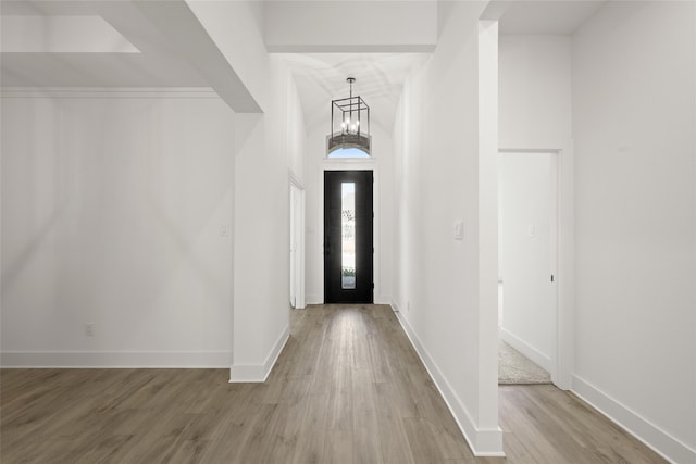 foyer entrance with light hardwood / wood-style floors and a notable chandelier