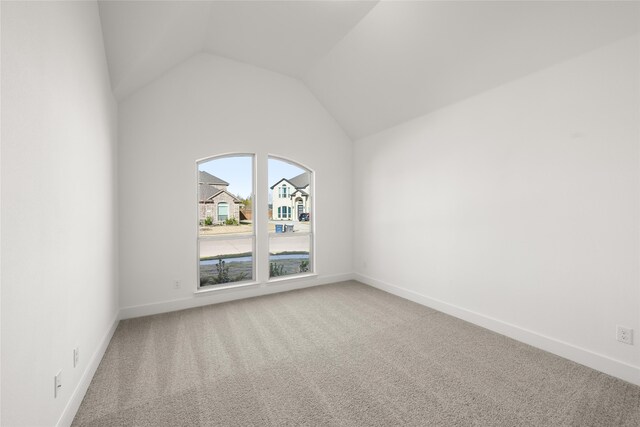 spare room with carpet flooring and lofted ceiling