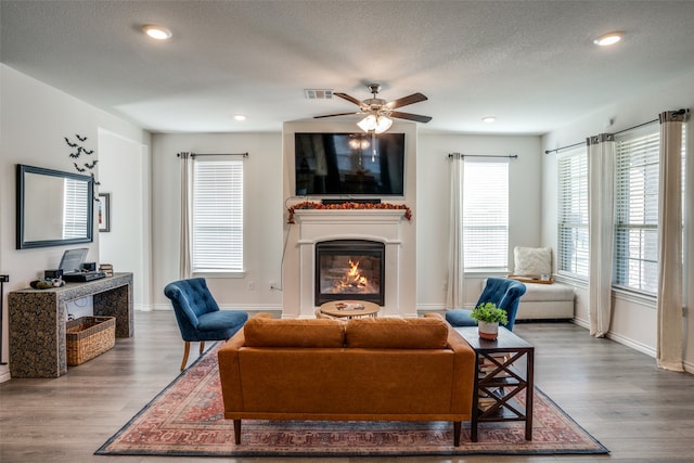 living room with dark hardwood / wood-style flooring, ceiling fan, and plenty of natural light