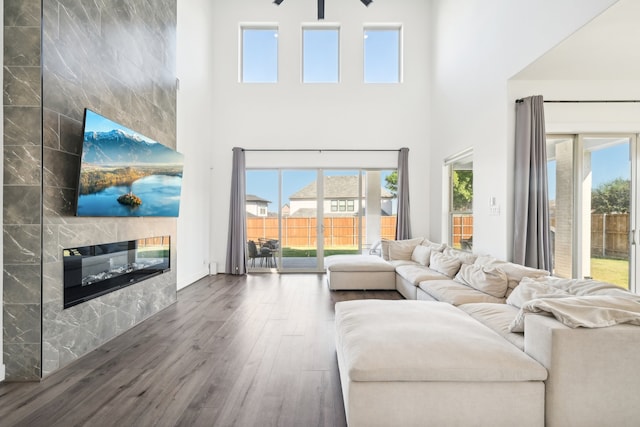 living room with a high ceiling, a fireplace, and dark hardwood / wood-style flooring