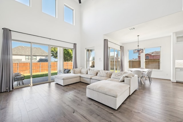 living room featuring hardwood / wood-style flooring, a towering ceiling, and a chandelier