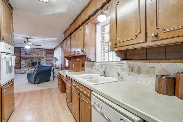 kitchen featuring ceiling fan, light wood-type flooring, a fireplace, sink, and white appliances