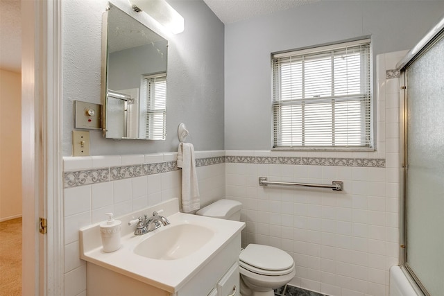 bathroom with toilet, vanity, tile walls, a textured ceiling, and walk in shower