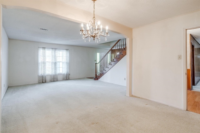 unfurnished room with a textured ceiling, carpet floors, and an inviting chandelier