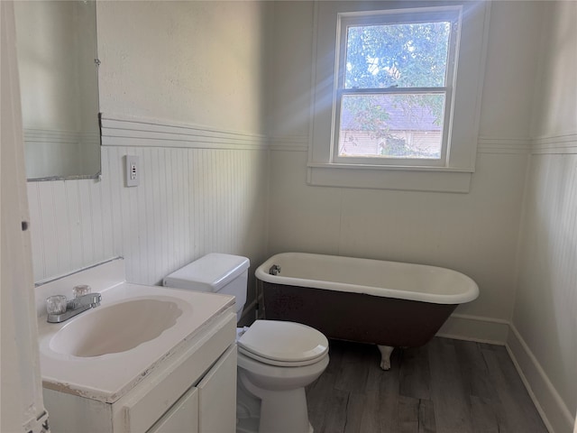 bathroom with toilet, a tub, vanity, and wood-type flooring