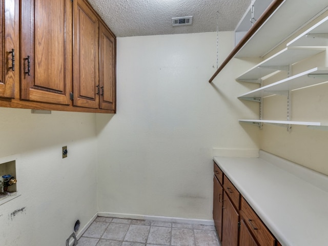 laundry area featuring hookup for a washing machine, electric dryer hookup, a textured ceiling, and cabinets