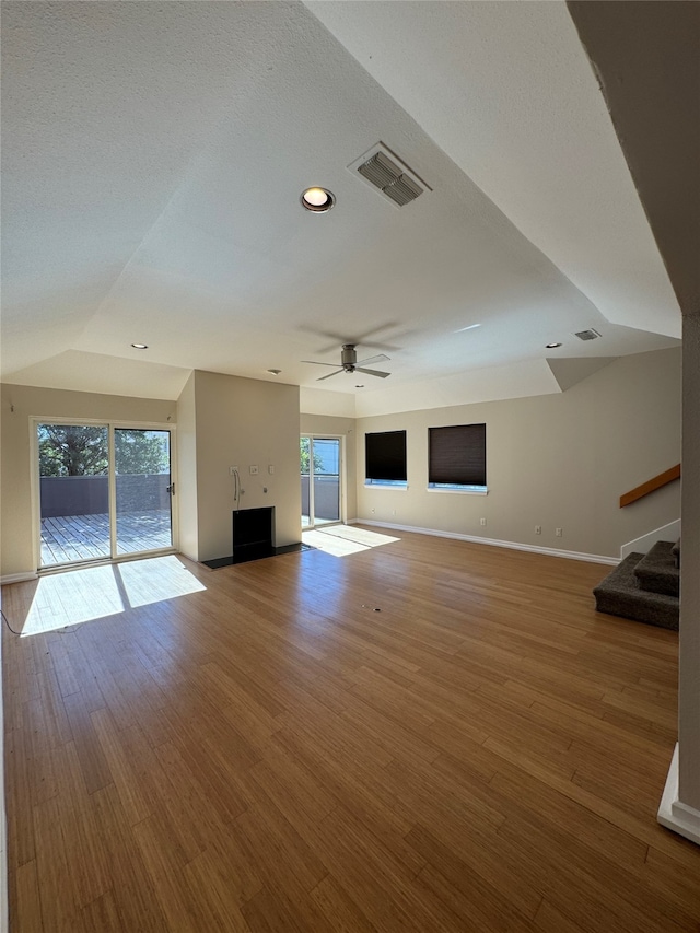 unfurnished living room with a wealth of natural light, vaulted ceiling, hardwood / wood-style flooring, and ceiling fan