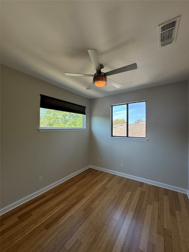 empty room featuring a textured ceiling, wood-type flooring, and ceiling fan