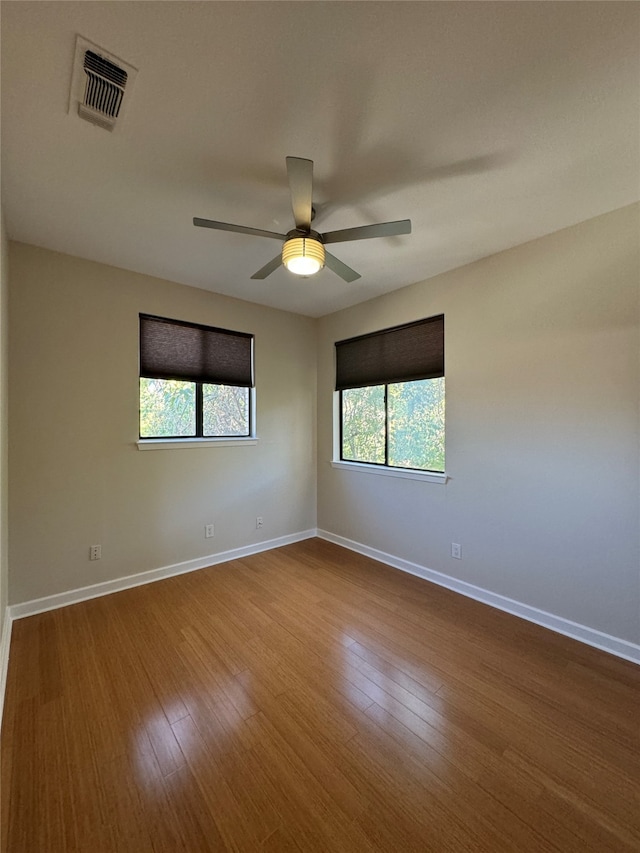 empty room featuring hardwood / wood-style flooring, ceiling fan, and a wealth of natural light