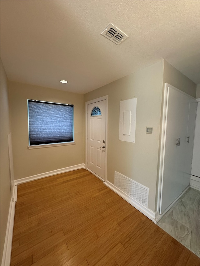 foyer entrance with a textured ceiling, hardwood / wood-style flooring, and electric panel