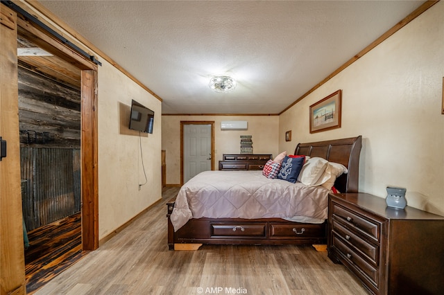 bedroom featuring ornamental molding, a wall unit AC, a textured ceiling, and wood finished floors