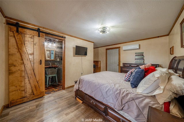 bedroom with a wall unit AC, a barn door, ornamental molding, and wood finished floors