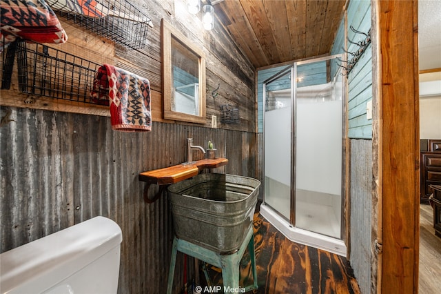 bathroom featuring toilet, wooden walls, wood finished floors, wood ceiling, and a stall shower