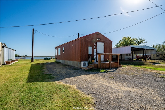 exterior space with a water view, a lawn, and an outbuilding