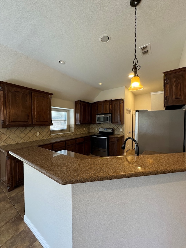 kitchen featuring appliances with stainless steel finishes, sink, kitchen peninsula, vaulted ceiling, and decorative light fixtures