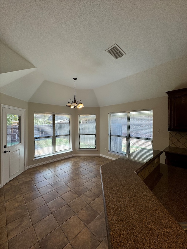 kitchen featuring lofted ceiling, a notable chandelier, a textured ceiling, and dark tile patterned flooring