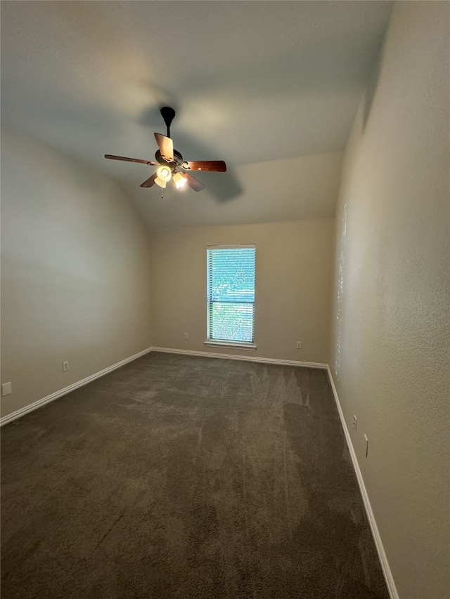 empty room with ceiling fan, dark carpet, and vaulted ceiling