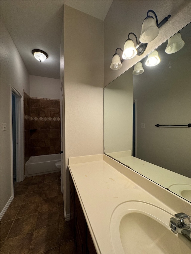 bathroom with vanity, a tile shower, toilet, and tile patterned flooring