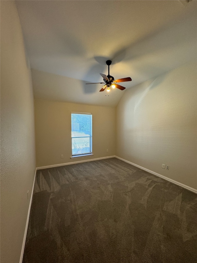 empty room featuring ceiling fan, lofted ceiling, and dark colored carpet