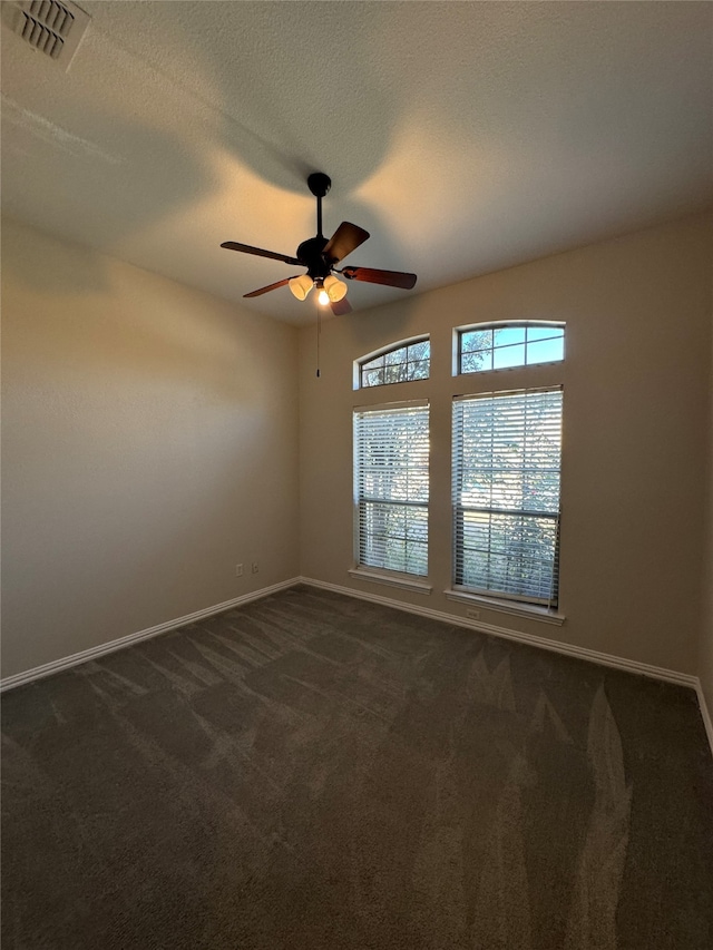 empty room featuring dark carpet, a textured ceiling, and ceiling fan