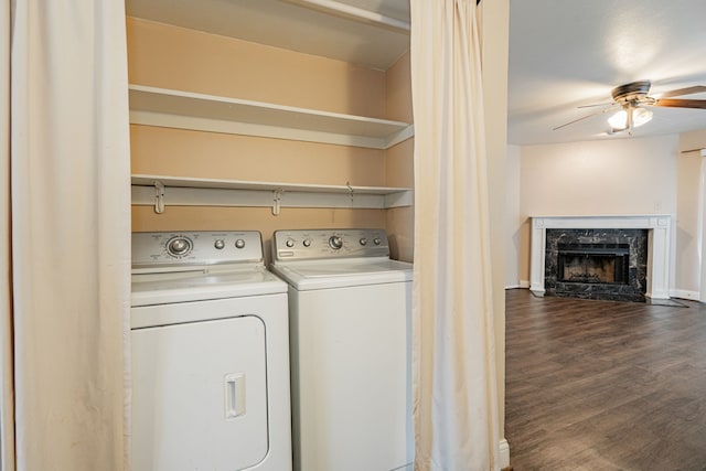 laundry room with washing machine and clothes dryer, ceiling fan, a fireplace, and dark hardwood / wood-style floors