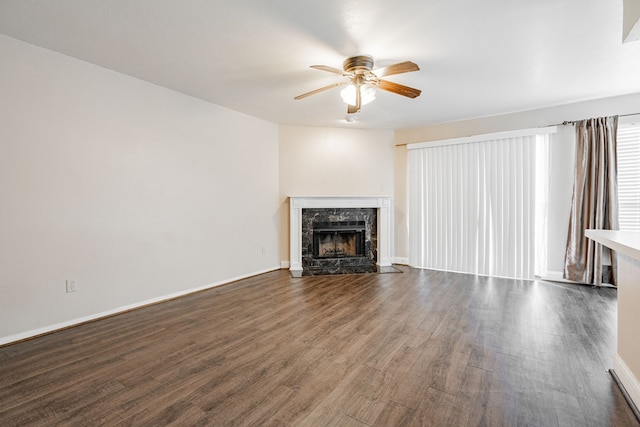 unfurnished living room with dark wood-type flooring, a tile fireplace, and ceiling fan