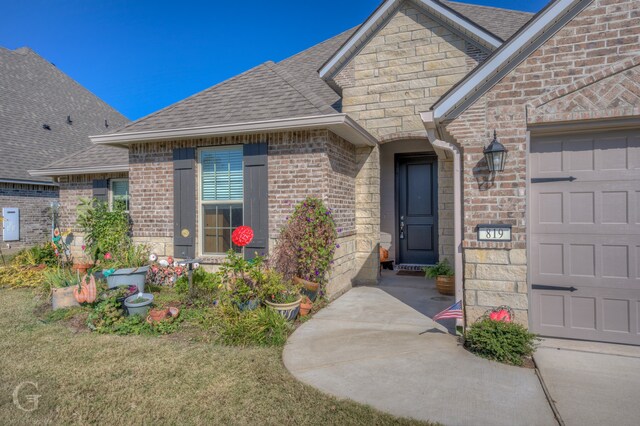 view of exterior entry featuring a garage and a lawn