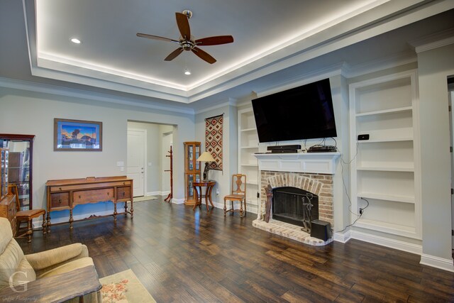 living room featuring a fireplace, ornamental molding, built in features, and dark hardwood / wood-style flooring