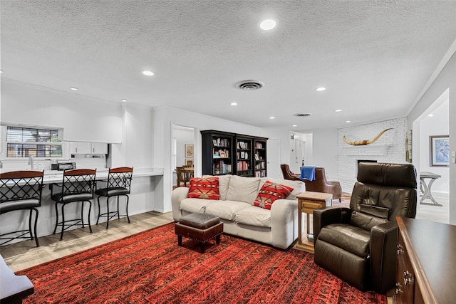 living room with wood-type flooring, a textured ceiling, and crown molding