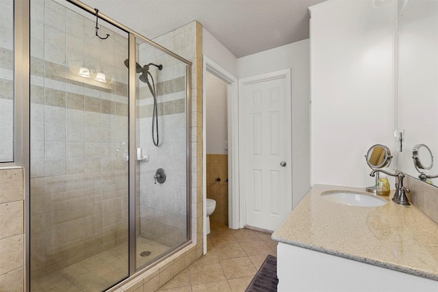 bathroom with tile patterned flooring, vanity, toilet, and a shower with door