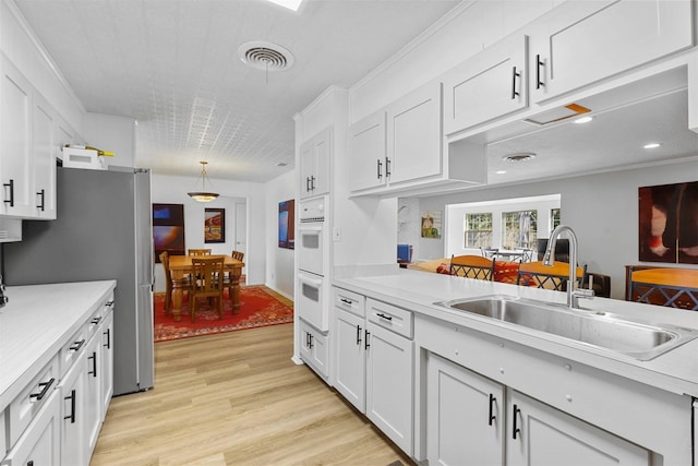 kitchen with white cabinetry, sink, and crown molding