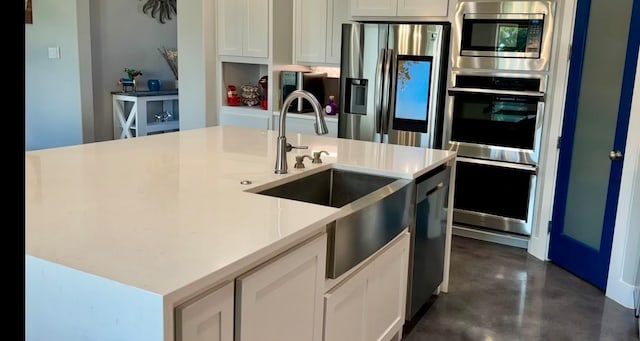 kitchen featuring white cabinets, stainless steel appliances, a center island with sink, and sink