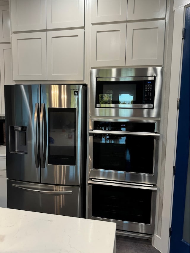 kitchen with white cabinetry, light stone countertops, and appliances with stainless steel finishes