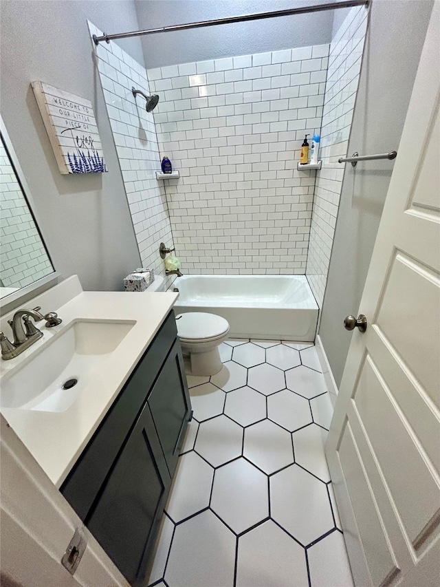 full bathroom featuring toilet, tiled shower / bath, vanity, and tile patterned flooring