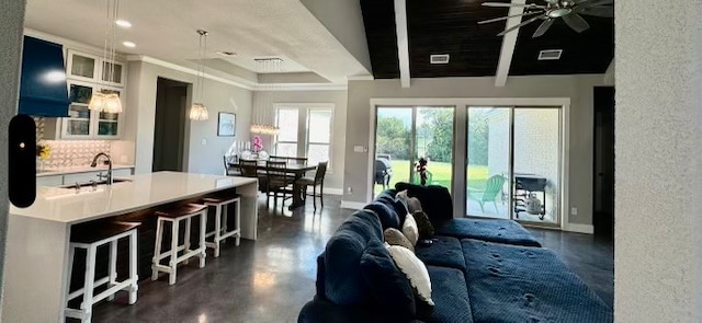 living room with beam ceiling, ornamental molding, sink, and ceiling fan