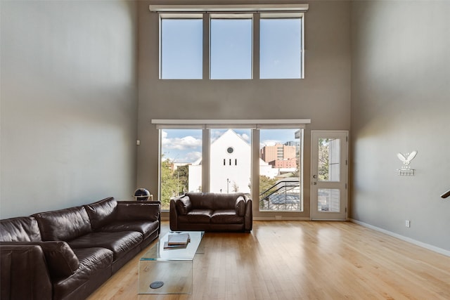 living room with a towering ceiling, light hardwood / wood-style flooring, and a wealth of natural light