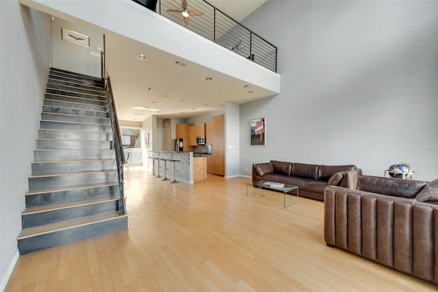 living room with light hardwood / wood-style flooring and a towering ceiling