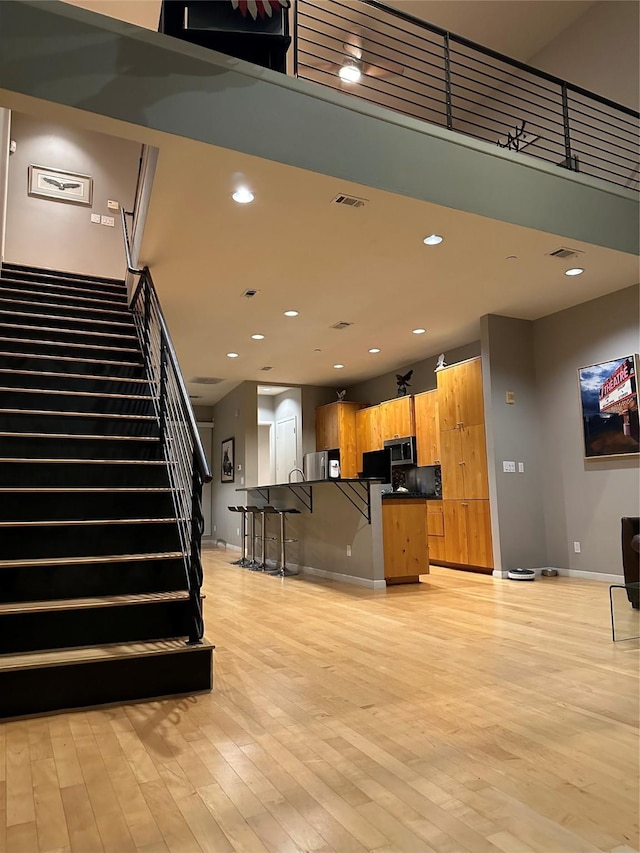 959 W Bluff St Unit 105, Fort Worth, TX 76102 - kitchen featuring dark countertops, light wood-style floors, a kitchen breakfast bar, a center island with sink, and stainless steel microwave
