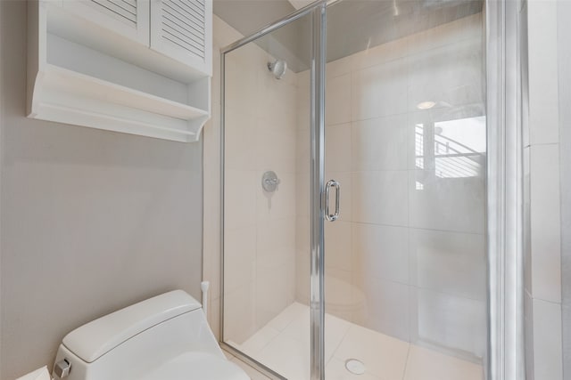 bathroom featuring toilet and a shower with shower door