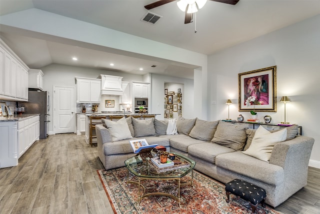 living room with light hardwood / wood-style floors, lofted ceiling, and ceiling fan