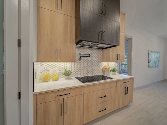 kitchen with black electric stovetop, light hardwood / wood-style floors, light brown cabinetry, and backsplash