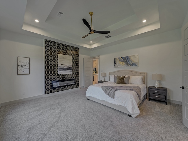 carpeted bedroom featuring ceiling fan and a tray ceiling