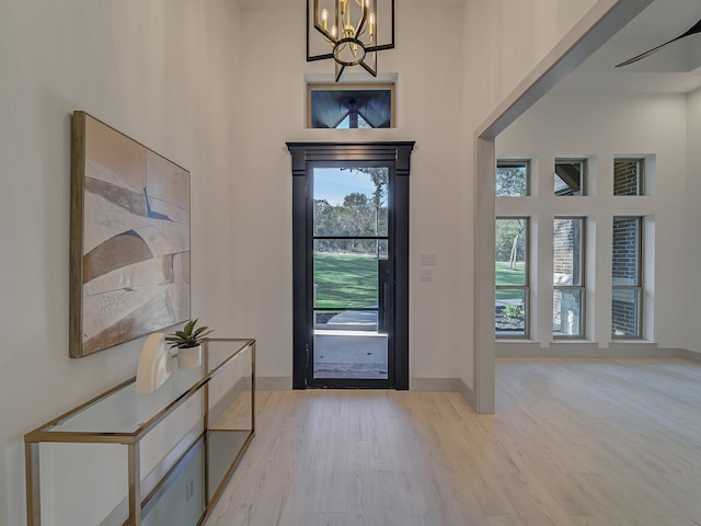 entryway with an inviting chandelier, a high ceiling, and light wood-type flooring