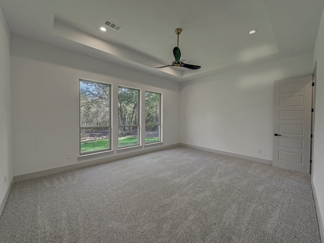 carpeted empty room featuring a tray ceiling and ceiling fan